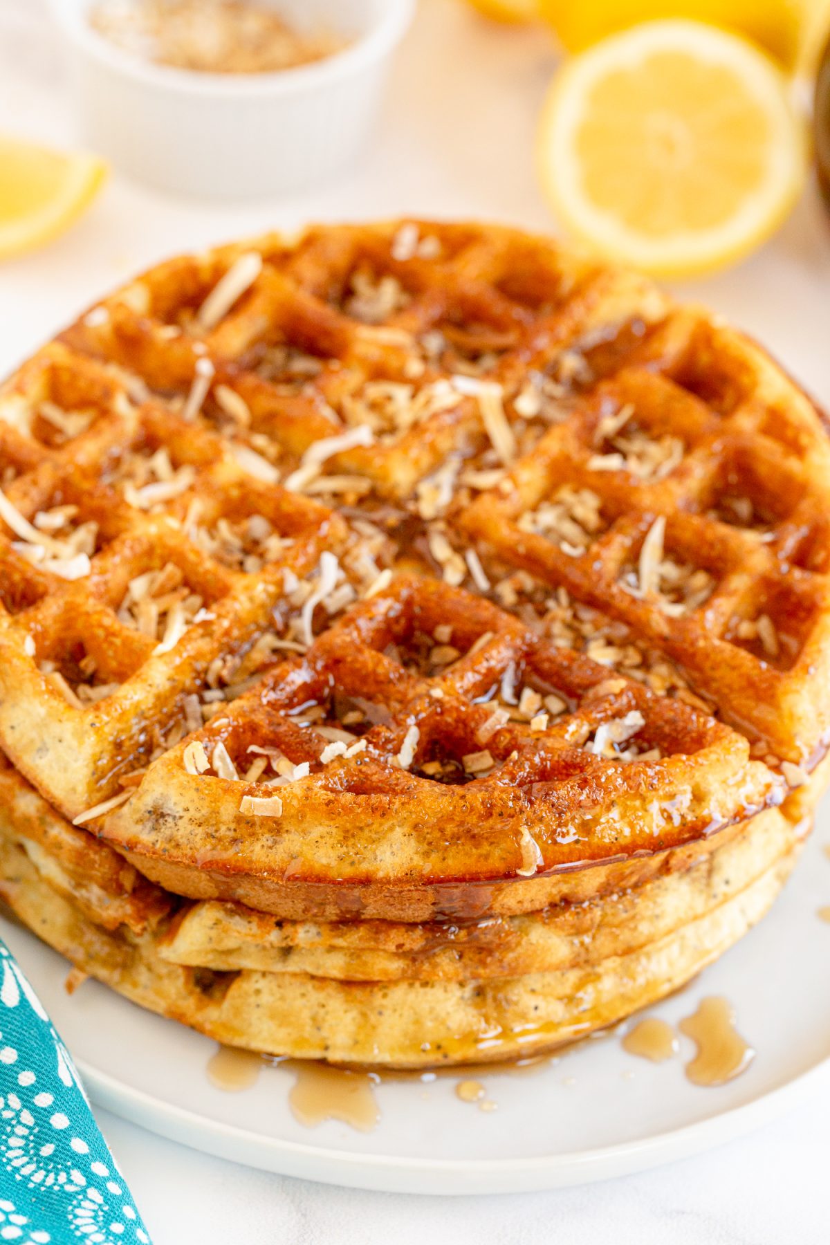 lemon coconut poppyseed waffle with shredded coconut and syrup on top of white plate