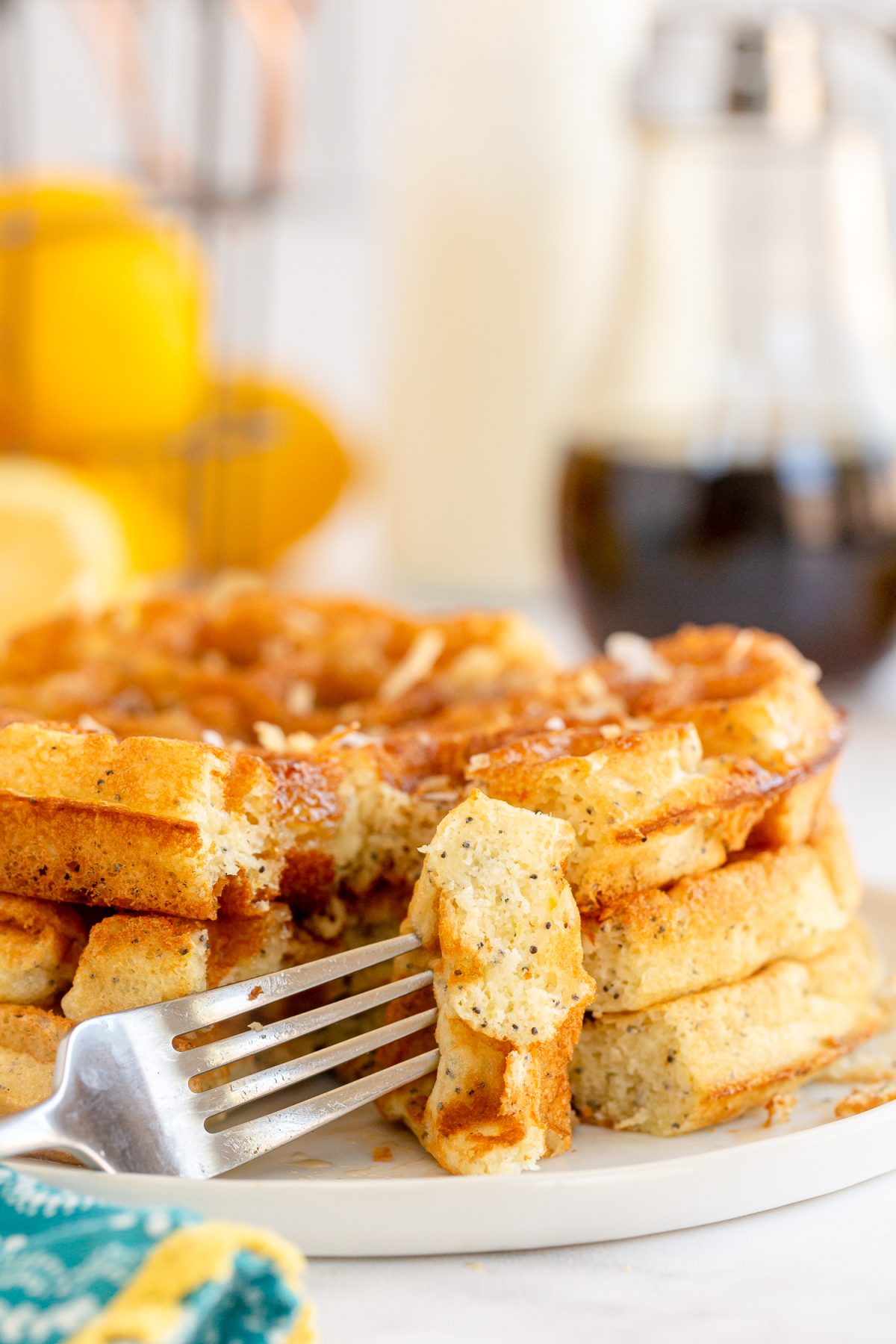 fork full of three waffles stack  on plate. 
